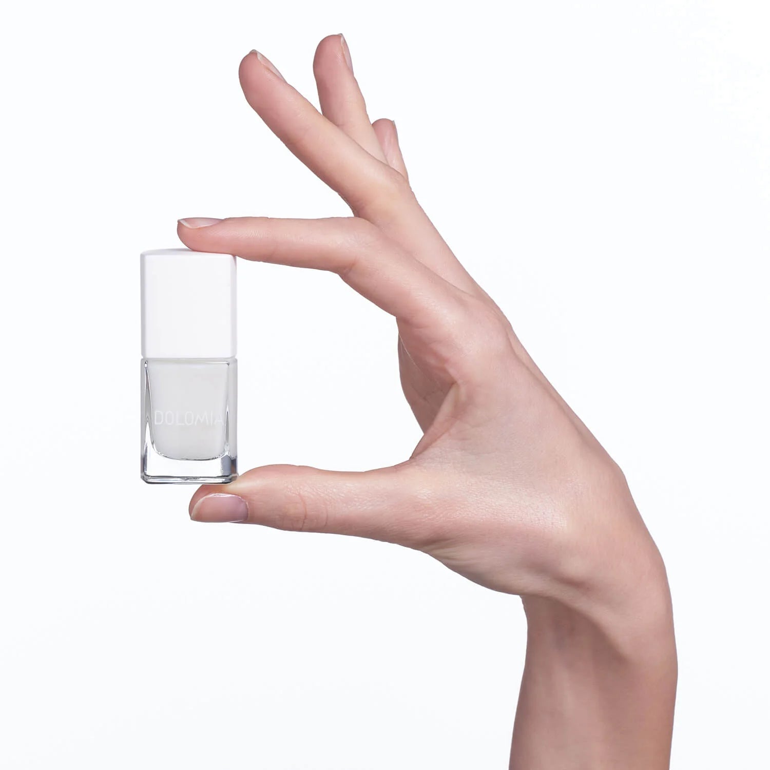 Eine Hand mit manikürten Nägeln hält eine kleine, klare Flasche Stärkende Nagellackbasis vor einem schlichten weißen Hintergrund - ideal zur Stärkung brüchiger Nägel.