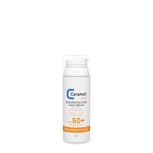 Eine weiße Flasche SUN PROTECTION FACE CREAM SPF 50+ mit orangefarbenem Etikett und Pumpspender ist vor einem schlichten, hellen Hintergrund abgebildet.